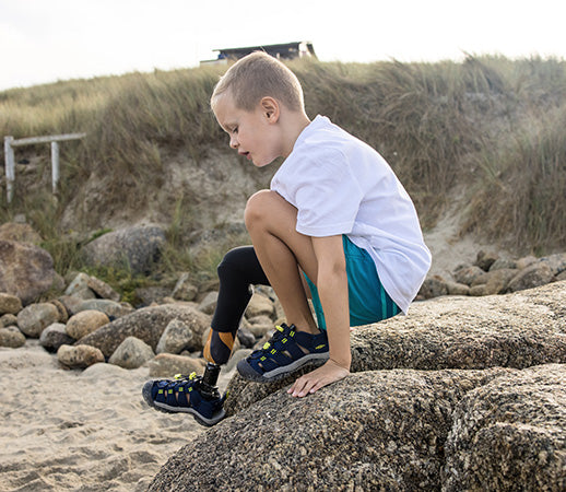 bambino in spiaggia sugli scogli che indossa sandali keen seacamp blue depths