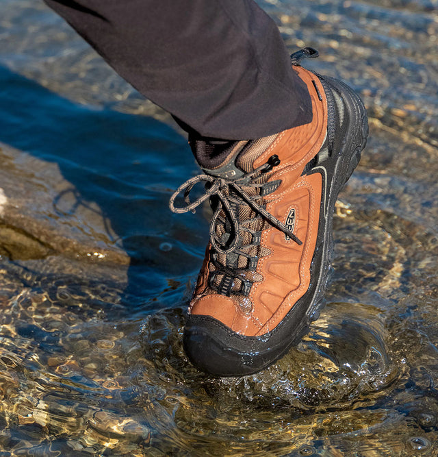 dettaglio uomo che cammina nell'acqua indossando scarponcino da trekking waterproof keen targhee IV orange